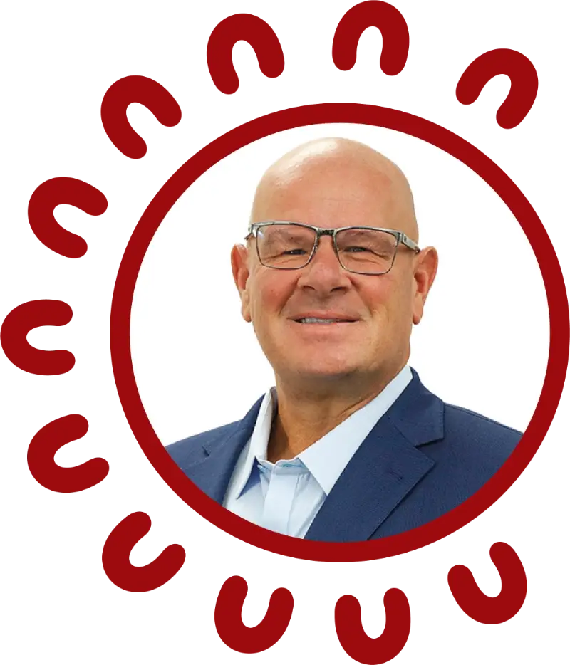 Circular portrait of Nicholas Pastras, Co-Founder of SCS Indigenous, a smiling middle-aged man with a shaved head, glasses, and a navy blue blazer over a light blue shirt, framed by a decorative red circular border of repeating U-shaped symbols inspired by Aboriginal art motifs, alongside a quote reading "Our vision for SCS Indigenous is to be a force of empowerment.